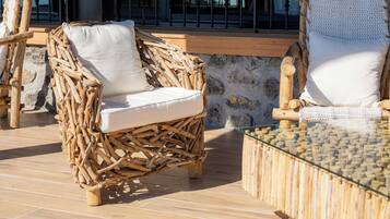 Wicker lounge chairs with white cushions on a wooden deck.