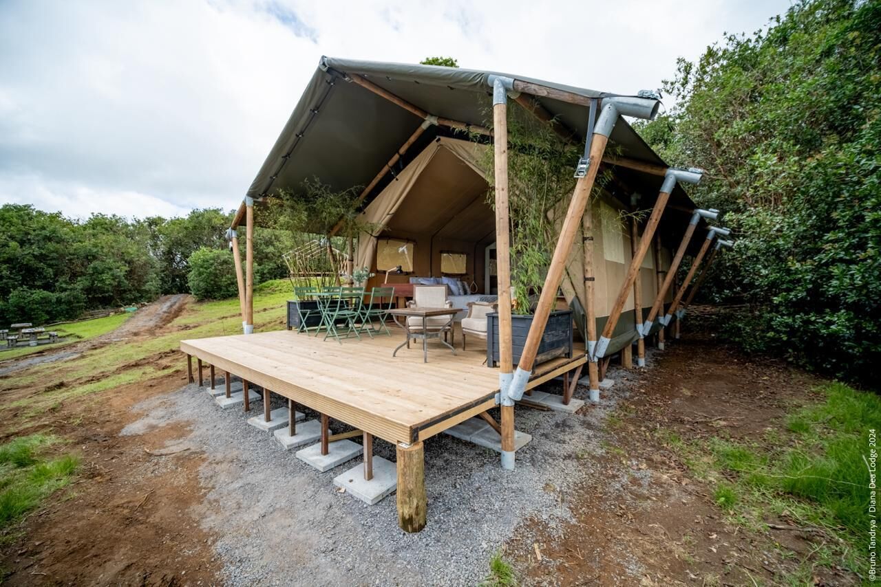 Una estructura tipo tienda con una terraza de madera, una zona de estar y una mesa.