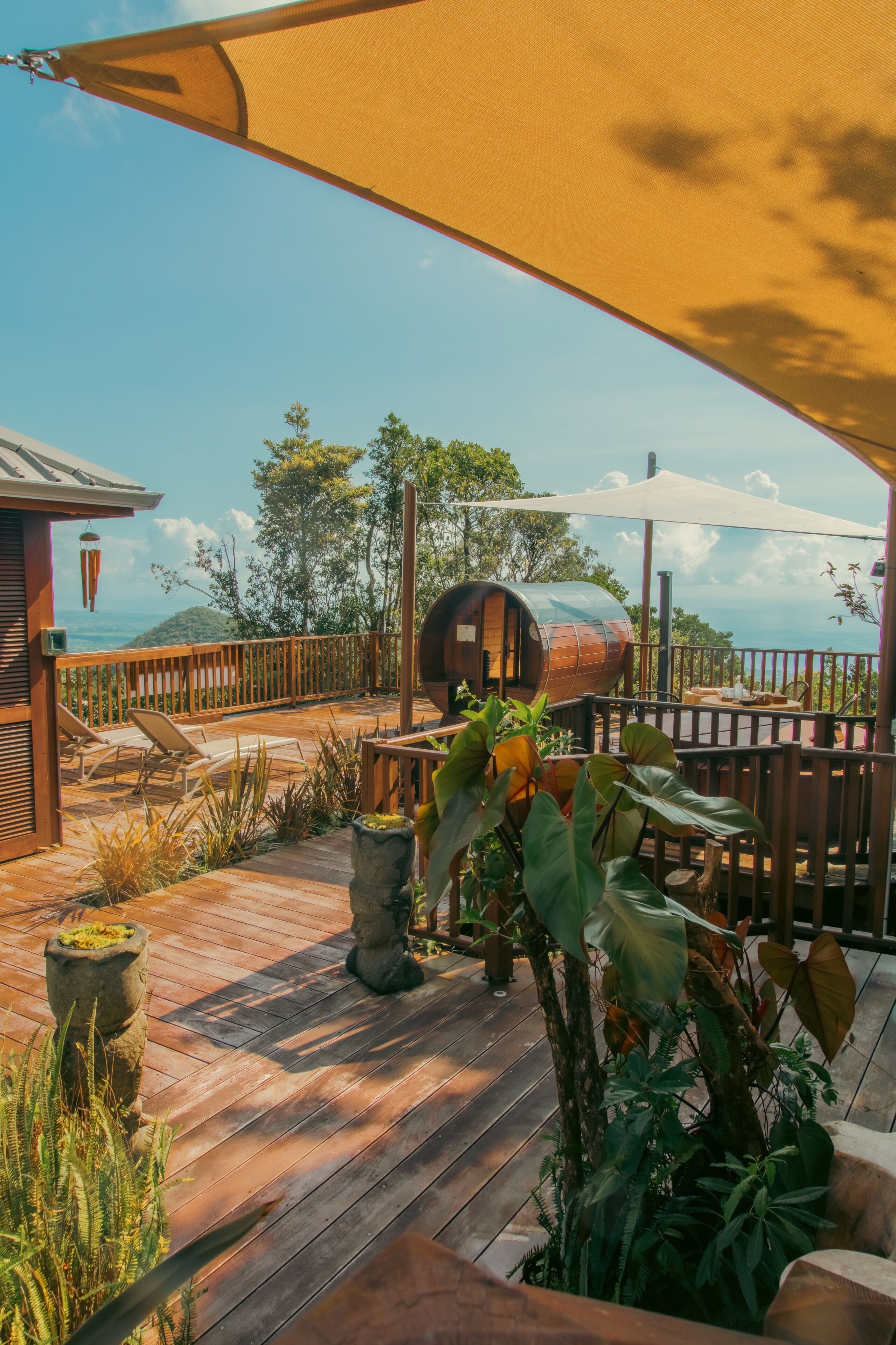 Une terrasse en bois avec des chaises longues, une structure en forme de tonneau en bois et une vue sur la mer.