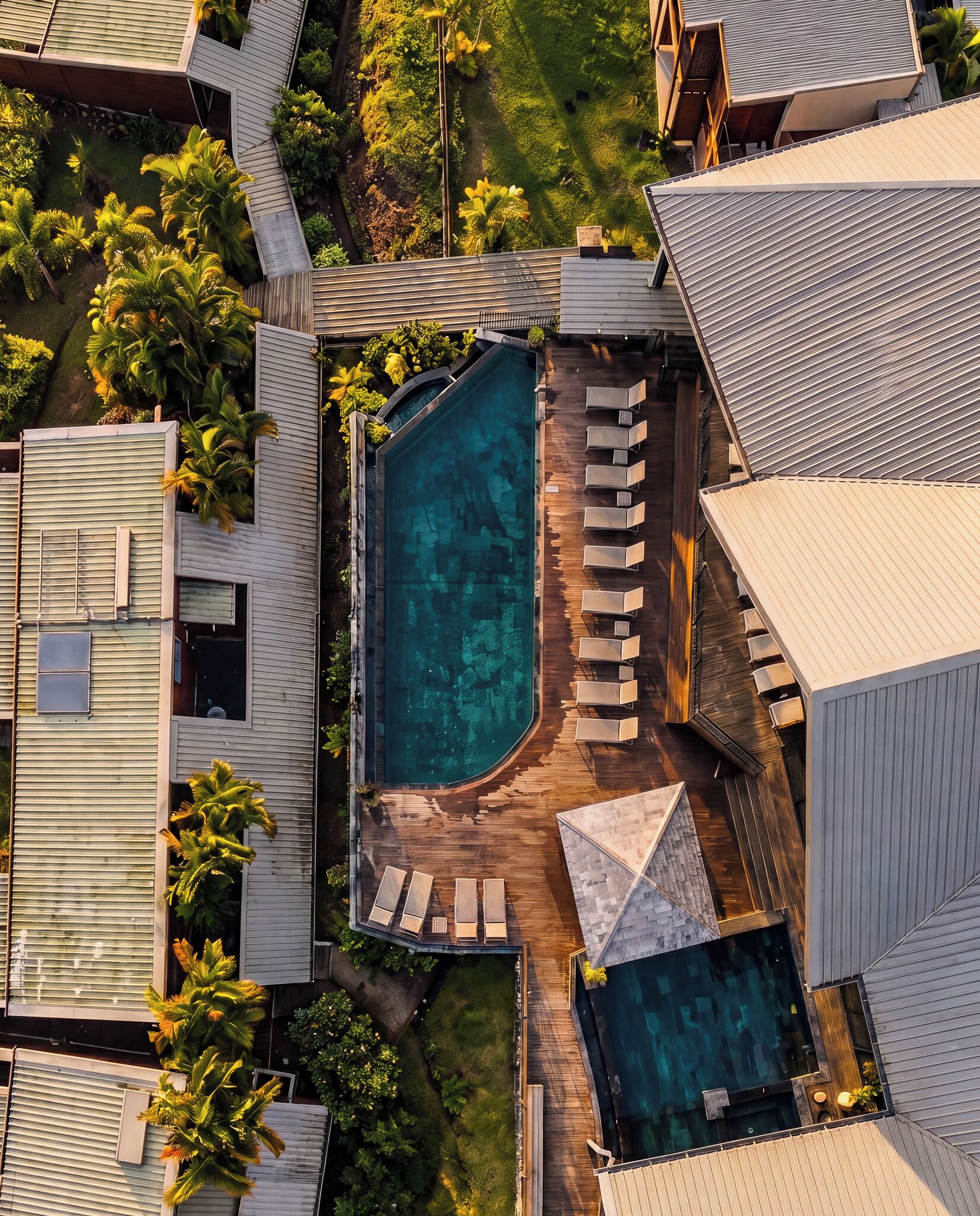 A residential property with a swimming pool, multiple lounge chairs, and a well-maintained garden.