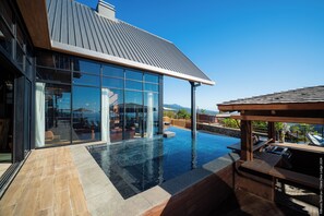 A modern house with a large glass window, a swimming pool, and a wooden deck. - Diana Dea Lodge (Saint-Benoit)