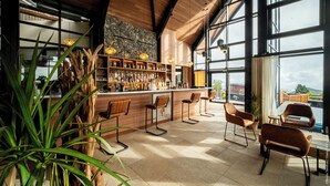 Uma área de bar com banquetas de madeira, uma parede de pedra e vista para o exterior.