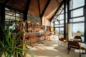 Un área de bar con taburetes de madera, pared de piedra y vistas al exterior.