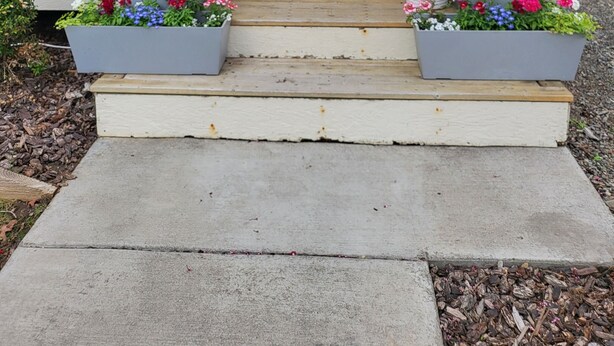 Eine Veranda mit einer roten Tür, Hausnummer 309, und zwei großen Blumenkästen auf den Stufen.