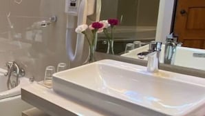 Ein modernes Badezimmer mit großem Spiegel, integriertem Waschbecken und Duschbrause.