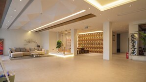 Eine großzügige Lobby mit modernem Design, ausgestattet mit einer Sitzecke, einem Sofa, einem Couchtisch, einem Empfangsbereich und einer Wand mit gerahmten Dekorationsobjekten.