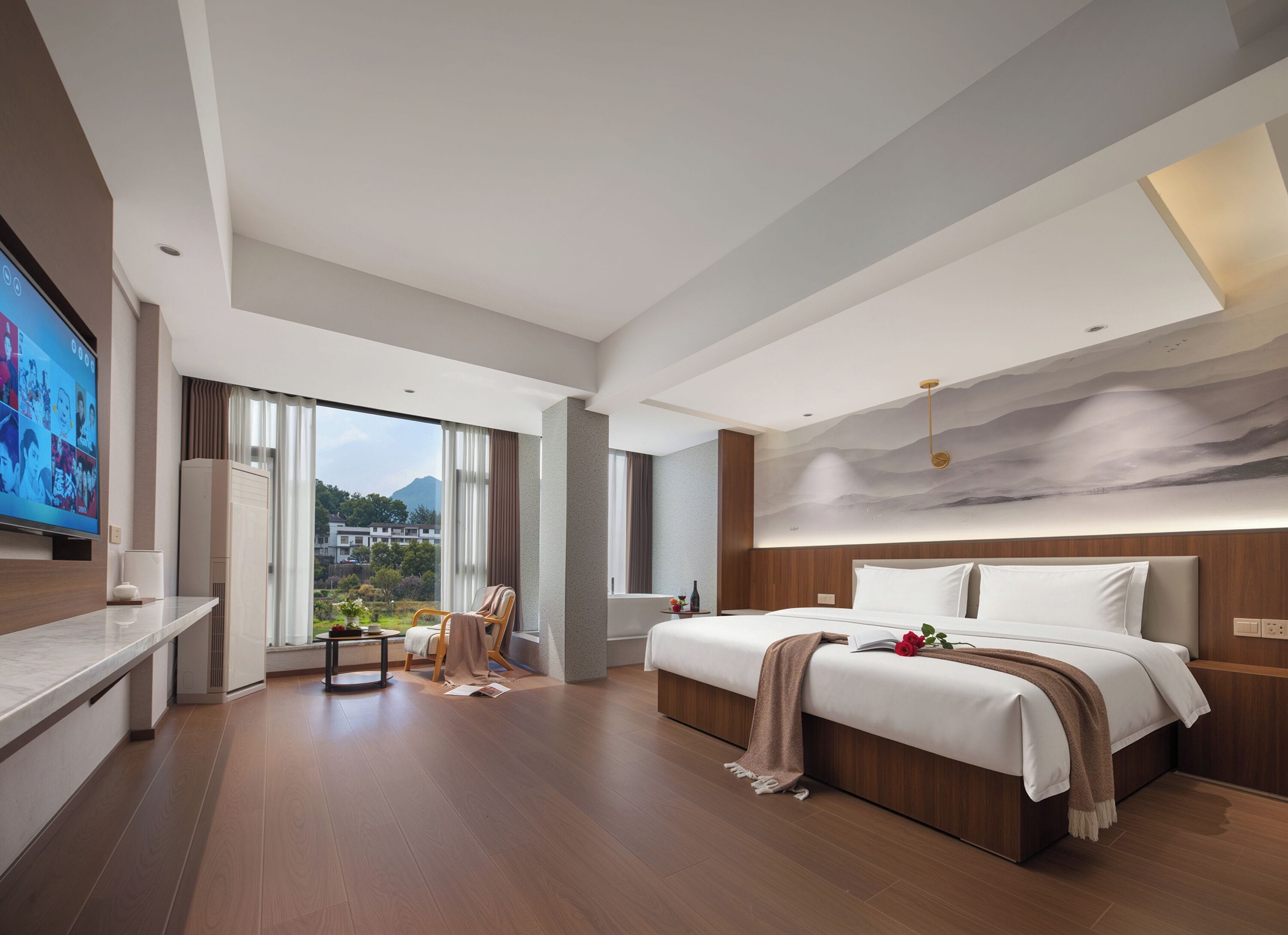 Una habitación de hotel moderna con una cama grande, un televisor y vistas a un paisaje montañoso.