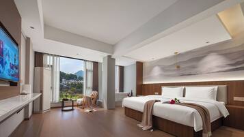 Una habitación de hotel moderna con una cama grande, un televisor y vistas a un paisaje montañoso.