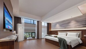 Ein modernes Hotelzimmer mit einem großen Bett, einem Flachbildfernseher und Blick ins Freie.