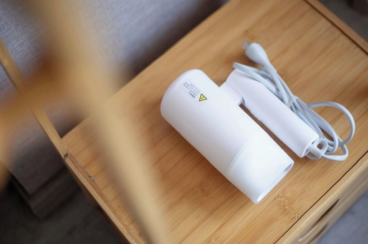 A white portable power bank with a cable on a wooden table.