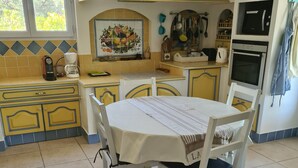 A kitchen with a dining table, chairs, and a tiled backsplash. - In a postcard setting! Villa 10 people Drome Provençale  (Buis-les-Baronnies)
