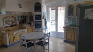 A kitchen with a dining table, chairs, a refrigerator, and a window with a view of the outside. - In a postcard setting! Villa 10 people Drome Provençale  (Buis-les-Baronnies)