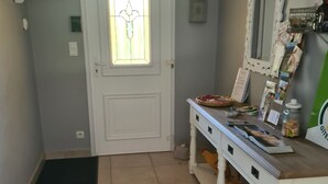 A hallway with a white door, a small window with a stained glass design, a white bench with various items, and a tiled floor. - In a postcard setting! Villa 10 people Drome Provençale  (Buis-les-Baronnies)