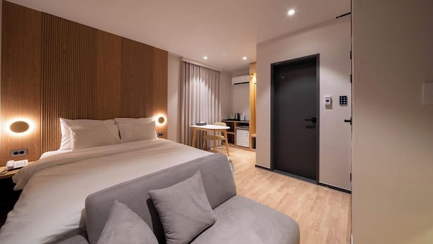 A modern hotel room with a large bed, a sofa, a desk, and a kitchenette. - Songdo Stay Sotam (Incheon)