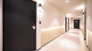 A hotel corridor with a dark wooden door, a number '201' sign, and a light-colored carpet. - Songdo Stay Sotam (Incheon)