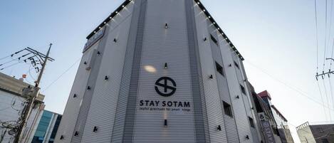 A tall, modern building with a sign reading "STAY SOTAM" and the tagline "Joyful gratitude for small things."