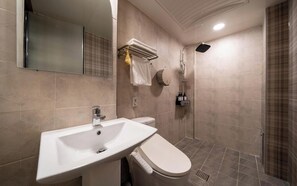 Un baño moderno con lavamanos, inodoro y ducha.