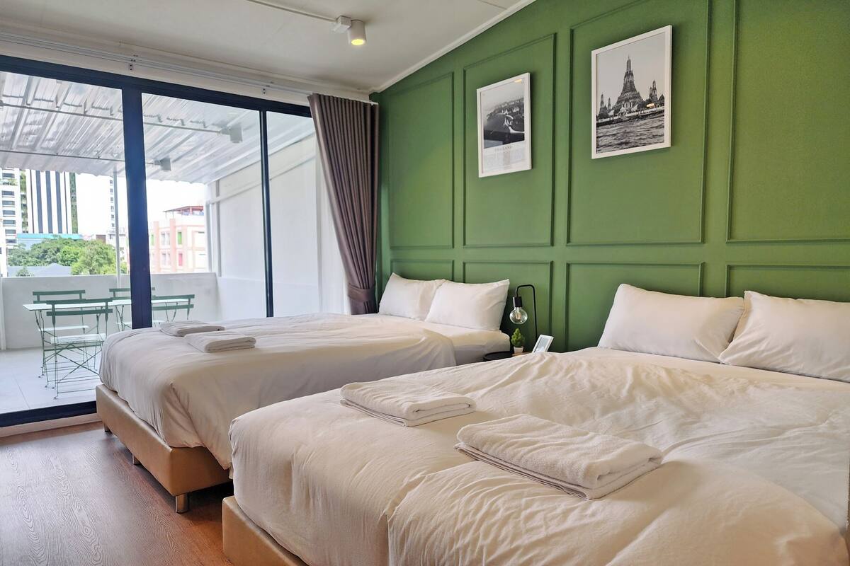 Een hotelkamer met twee bedden, een groene accentmuur en uitzicht op de stad.
