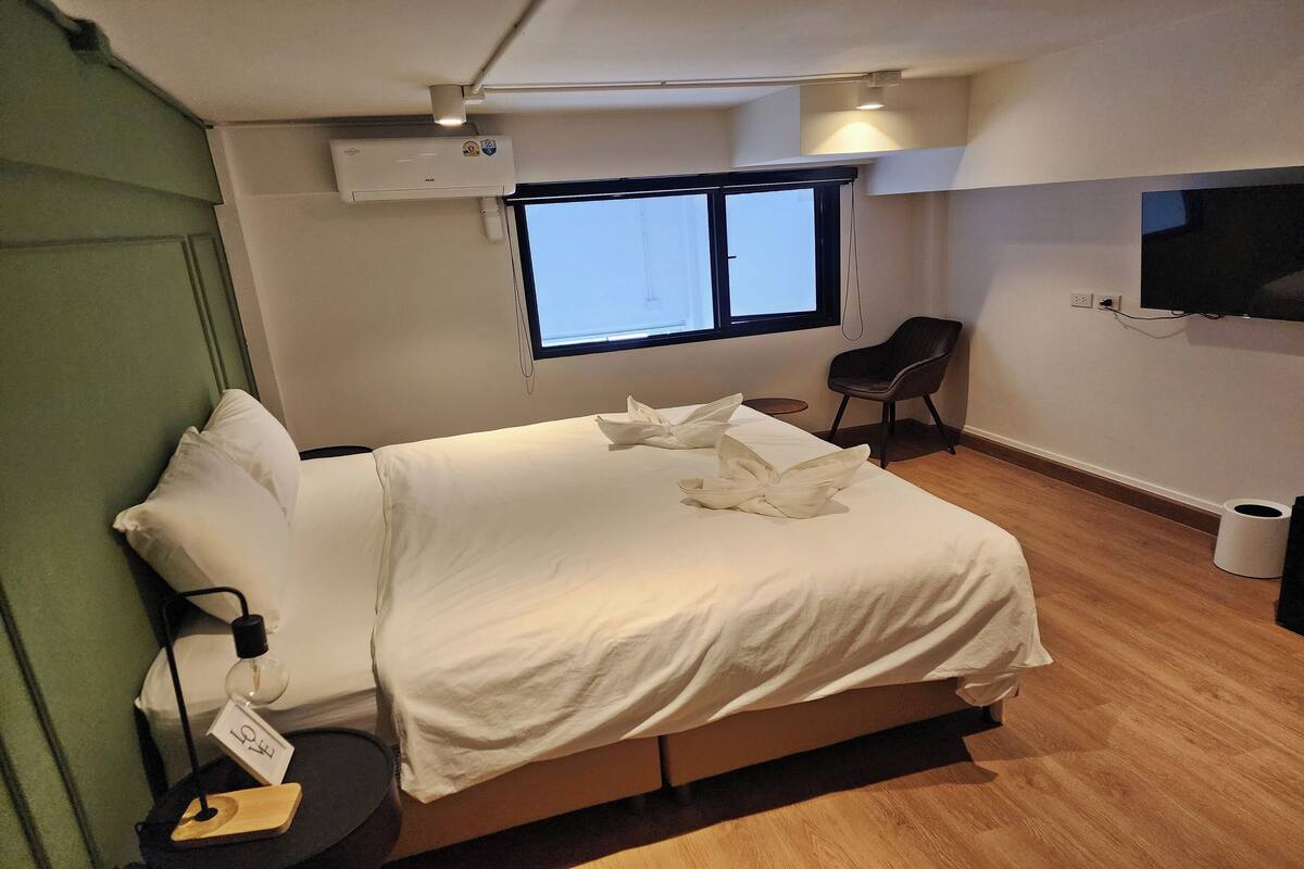 Een hotelkamer met een bed, een stoel, een televisie en een raam.