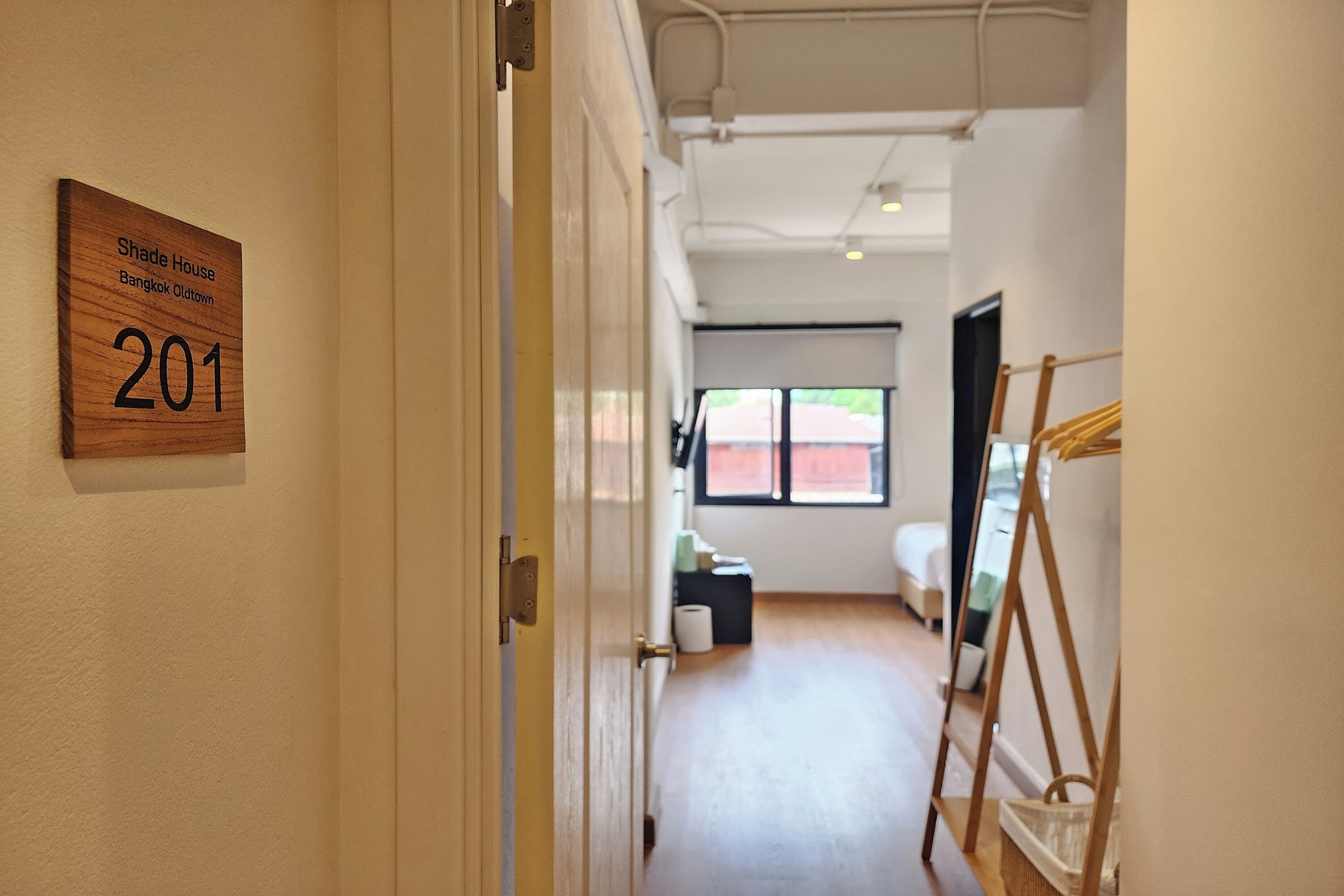 A hallway with a wooden sign indicating 'Shade House Bangkok Oldtown 201'.