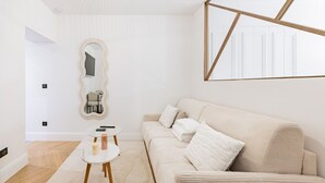 Ein schlicht eingerichtetes Wohnzimmer mit Sofa, rundem Spiegel und kleinem Beistelltisch.