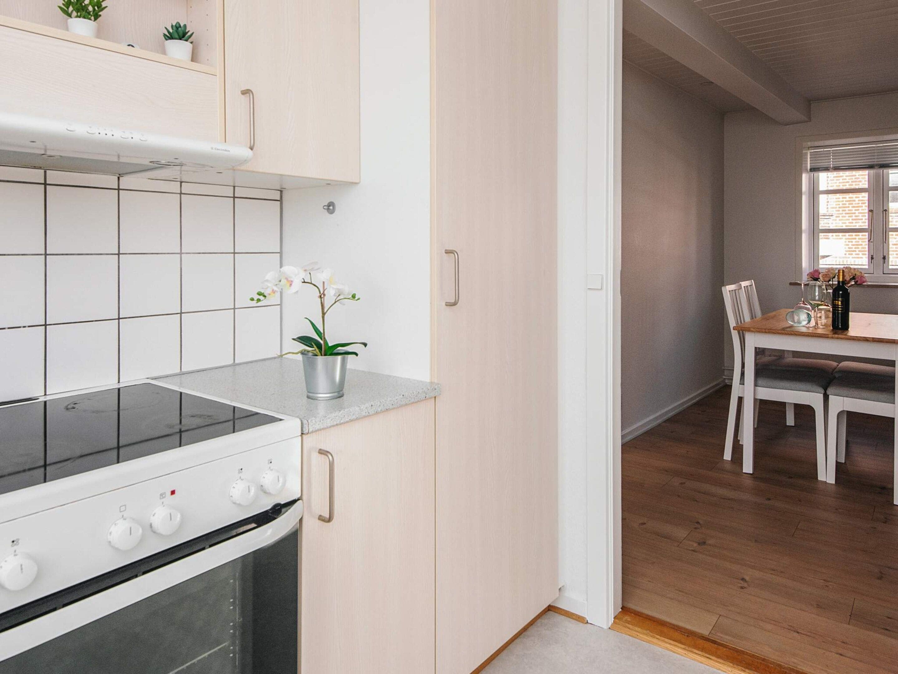A modern kitchen with a stove, cabinets, and a potted orchid on the countertop.
