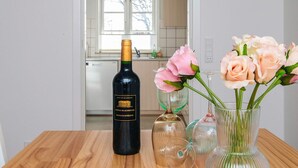 Een fles wijn, een vaas met bloemen en een glas op een houten tafel.