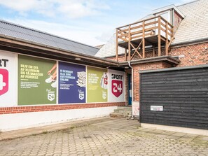 Un bâtiment à la façade en briques, une grande enseigne publicitaire pour « Klub Sport 24 » et une structure en bois sur le toit.