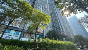 Een modern hoogbouwgebouw met meerdere verdiepingen, omgeven door weelderige begroeiing en bomen.