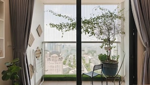 Een balkon met een bloempot, een stoel en uitzicht op de stad.