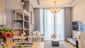 Een moderne woonkamer met een eethoek, een kroonluchter, een flatscreen televisie en een waterdispenser.