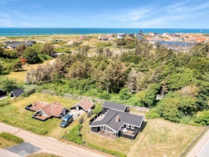 A residential area with houses, a road, and a view of the sea.