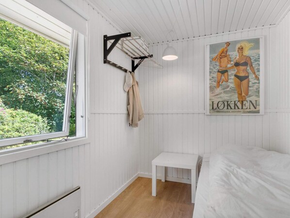 A room with a bed, a small table, a drying rack, and a poster on the wall.