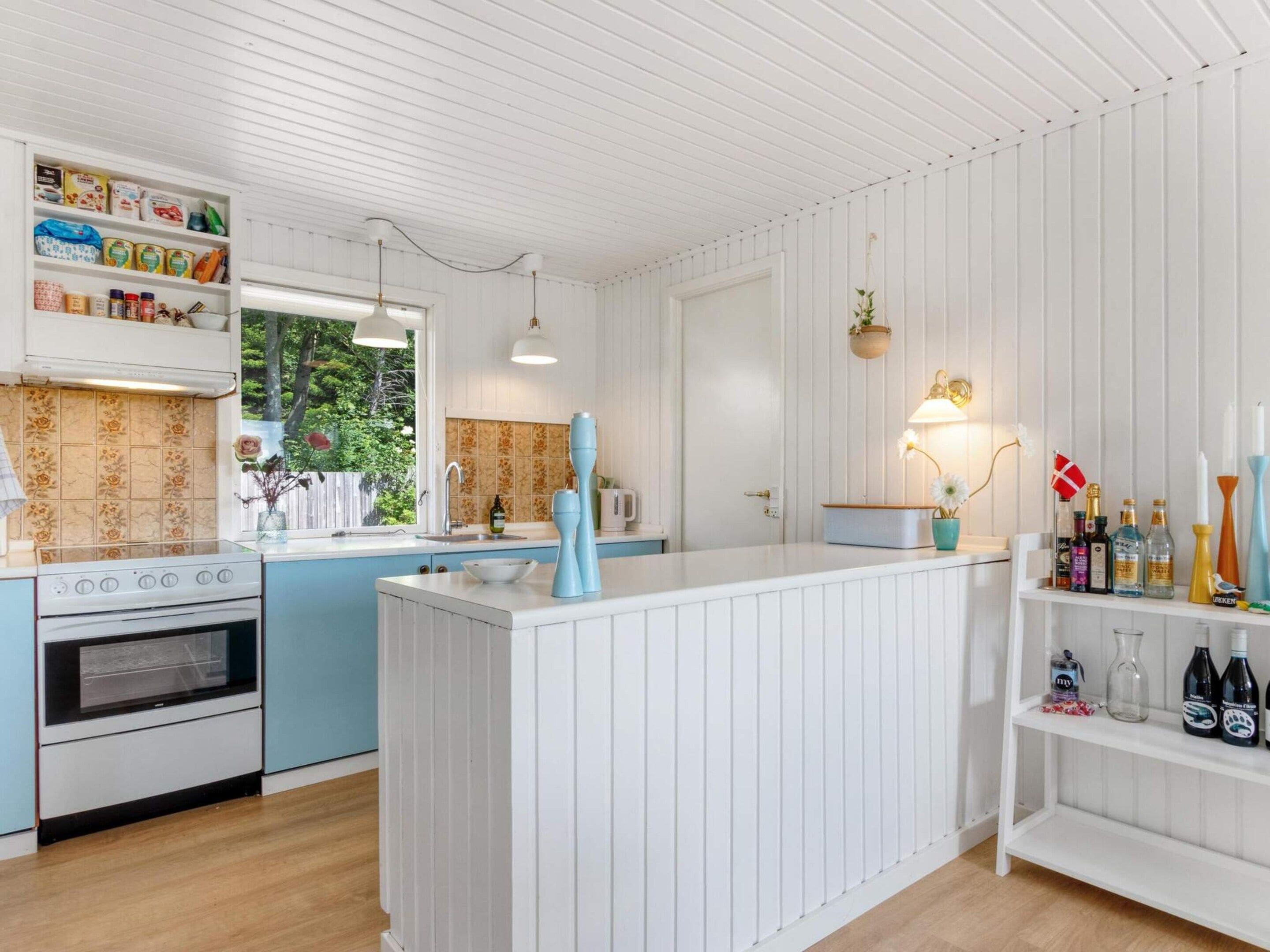 A kitchen with a central island, a stove, and a window with a view of greenery.