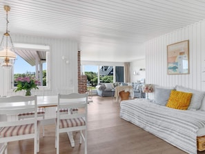 A spacious living area with a sofa, a dining table with chairs, and a view of the outdoors.