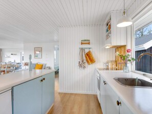 A modern kitchen with white cabinetry, a central island, and a window with a view.