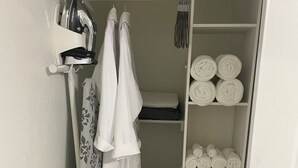 Une salle de bain avec un rideau de douche, un porte-serviettes mural et des étagères où sont rangées des serviettes pliées avec soin.