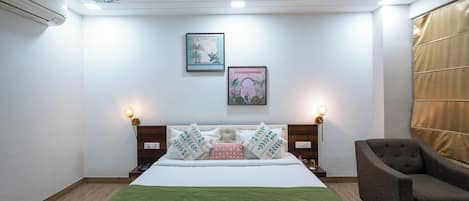 A neatly arranged hotel room with a bed, two wall-mounted lamps, a chair, and two framed pictures.