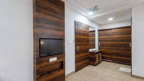 Una habitación moderna con paneles de madera, un televisor de pantalla plana y un mueble pequeño.