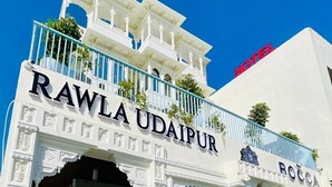 La entrada del hotel Rawla Udaipur, con diseño arquitectónico tradicional y un letrero.