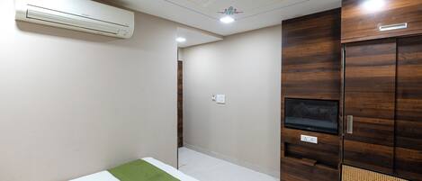 Un dormitorio con cama, un armario de madera, un televisor y aire acondicionado.