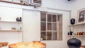 A room with white brick walls, a large window, and shelves displaying various pottery and vases. - 2 Person Holiday Home in Ringkobing (Ringkobing)