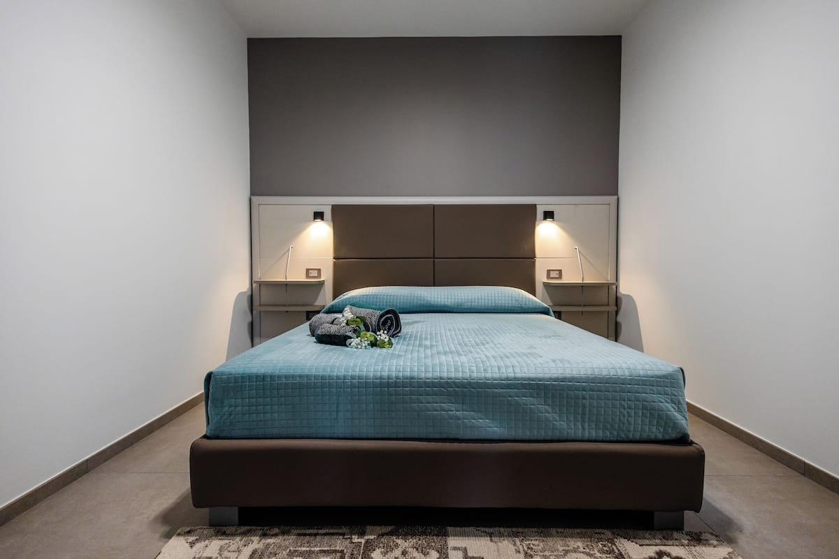 A modern bedroom with a large bed, two bedside tables, and a headboard.