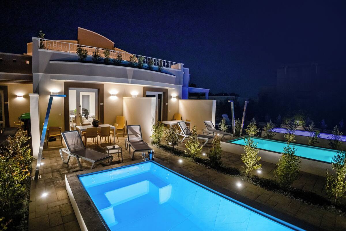 A modern two-story building with a swimming pool and outdoor seating area.