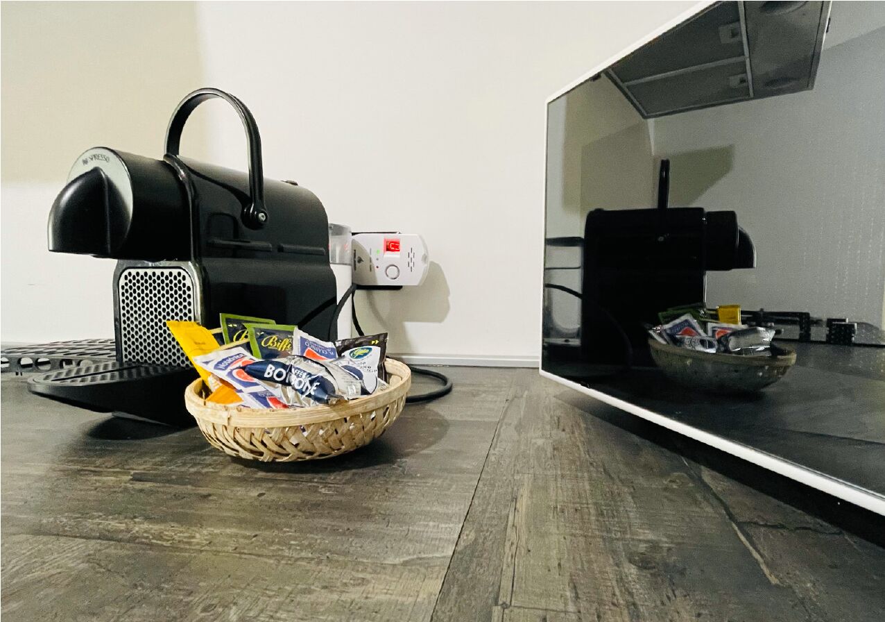 A kitchen with a coffee machine, a basket of snacks, and a microwave.