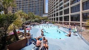 Uma área de piscina com várias piscinas, espreguiçadeiras e palmeiras.