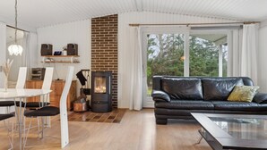 Un salon moderne avec une cheminée, un canapé en cuir noir, une table à manger avec des chaises et une grande fenêtre.
