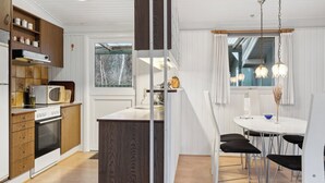 Une cuisine moderne avec des meubles en bois, un four à micro-ondes encastré et un coin repas comprenant une table ronde et des chaises.