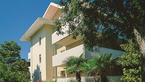 Un edificio de varios pisos con techo plano, rodeado de árboles y vegetación.