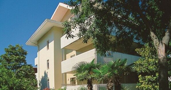 A multi-story building with a flat roof, surrounded by trees and greenery.
